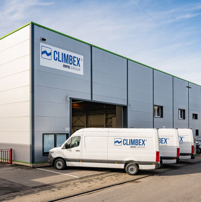 Climbex Gebäude von außen. Mehrere Firmen-Transporter stehen davor.