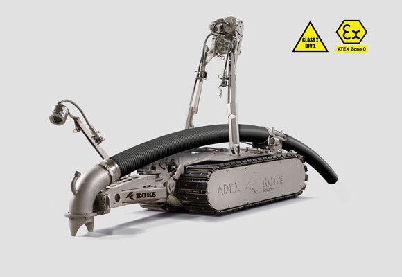 Roboter mit Schlauch, der Richtung Boden zeigt, und Kameras, zur Steuerung durch einen Mitarbeiter.