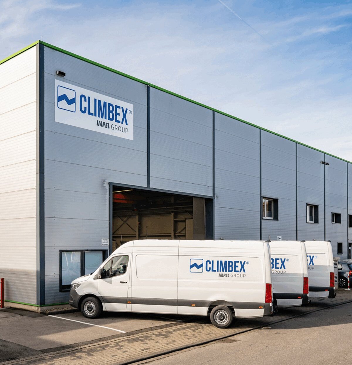 Climbex Gebäude von außen. Mehrere Firmen-Transporter stehen davor.